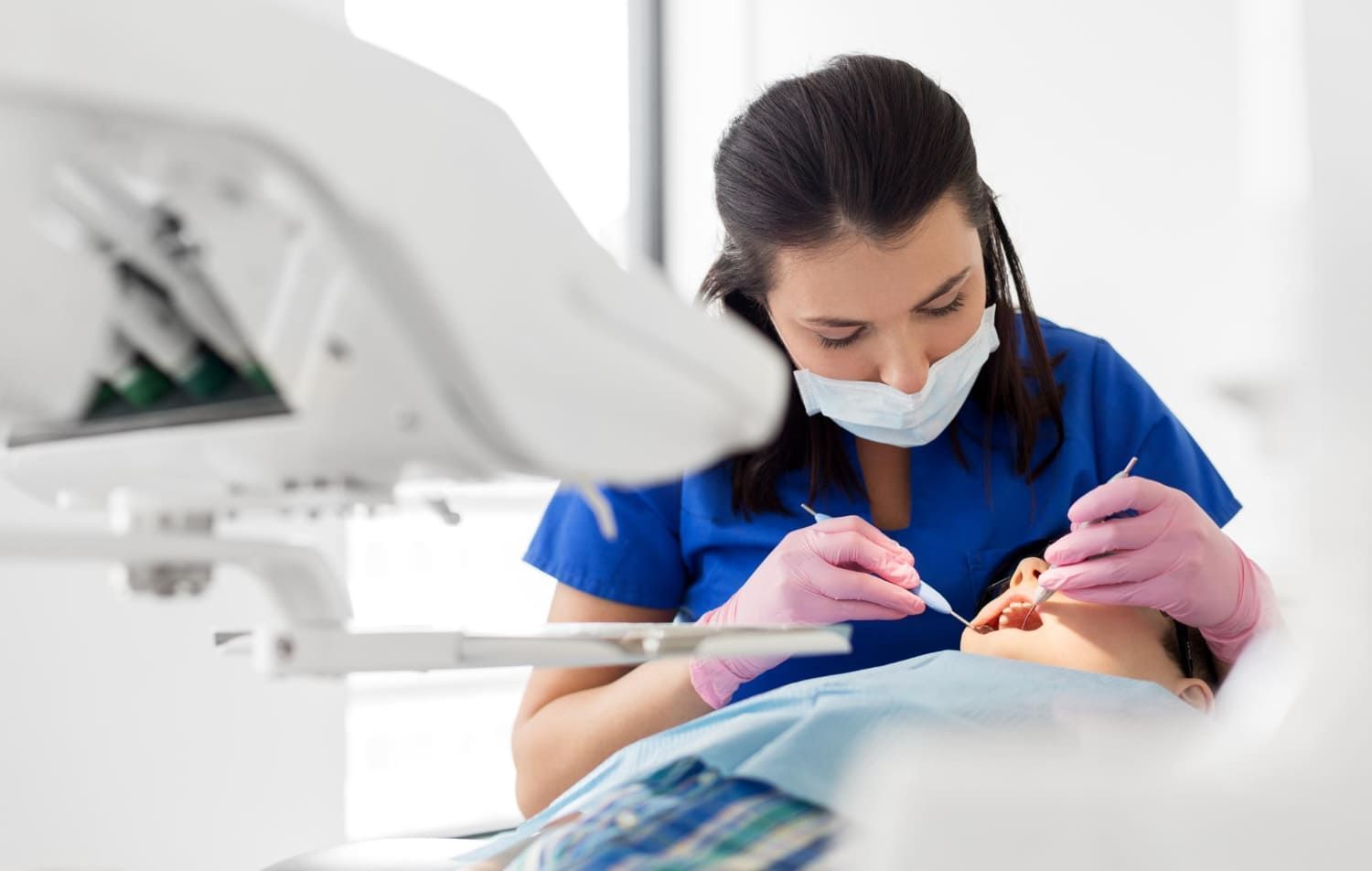 Mulher dentista atendendo um paciente no consultório; profissões que têm os maiores salários iniciais