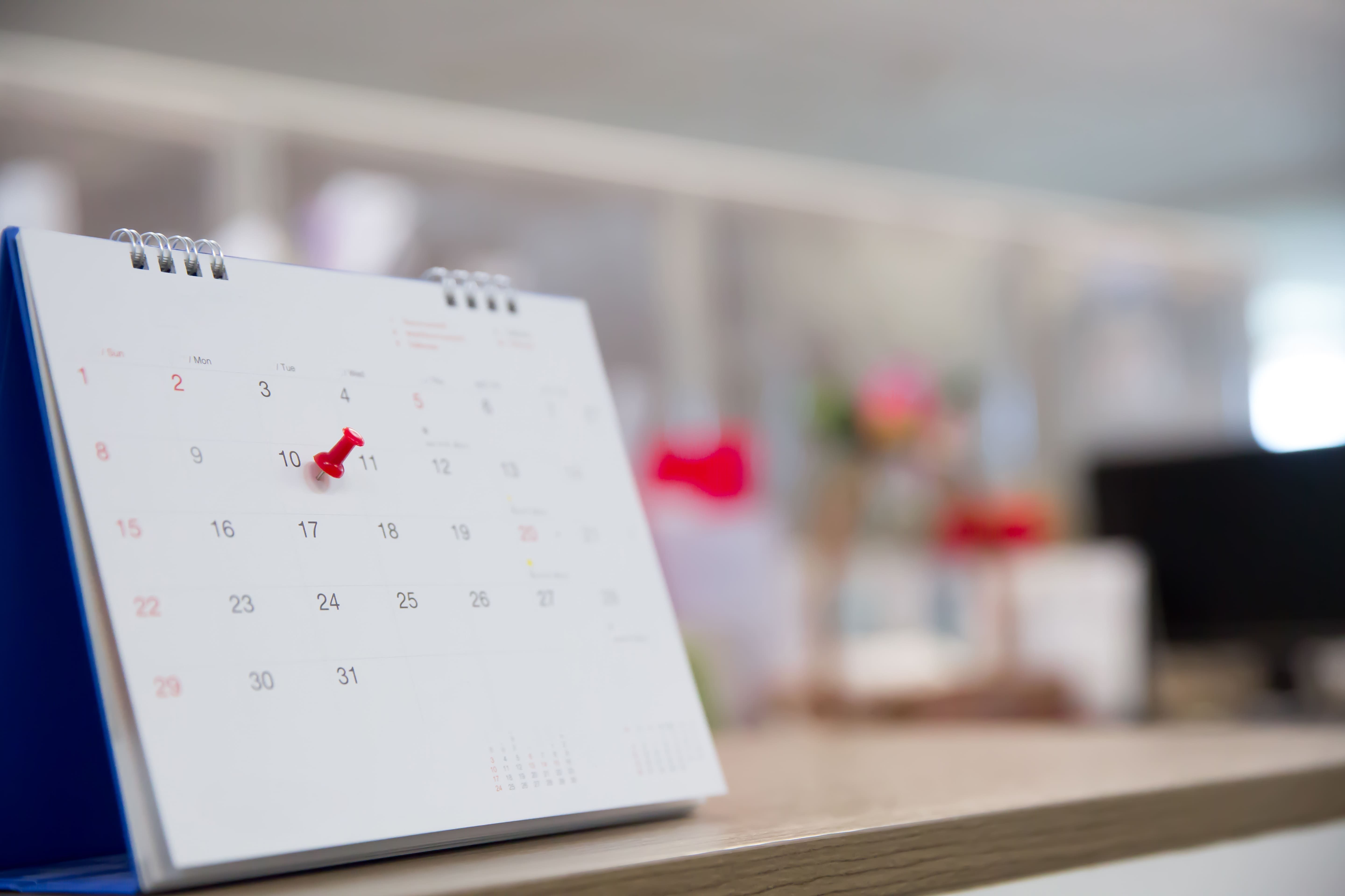 calendário em cima de mesa com pino vermelho inserido no dia 10