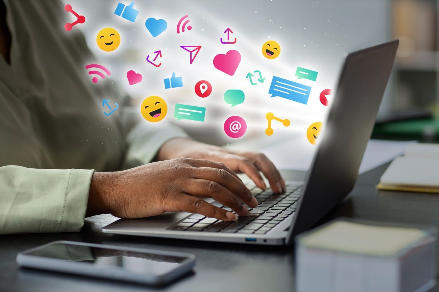 Mão de mulher teclando no computador com vários ícones de rede social em volta; 7 cursos de pós para quem quer trabalhar com Tiktok, Instagram e Twitter