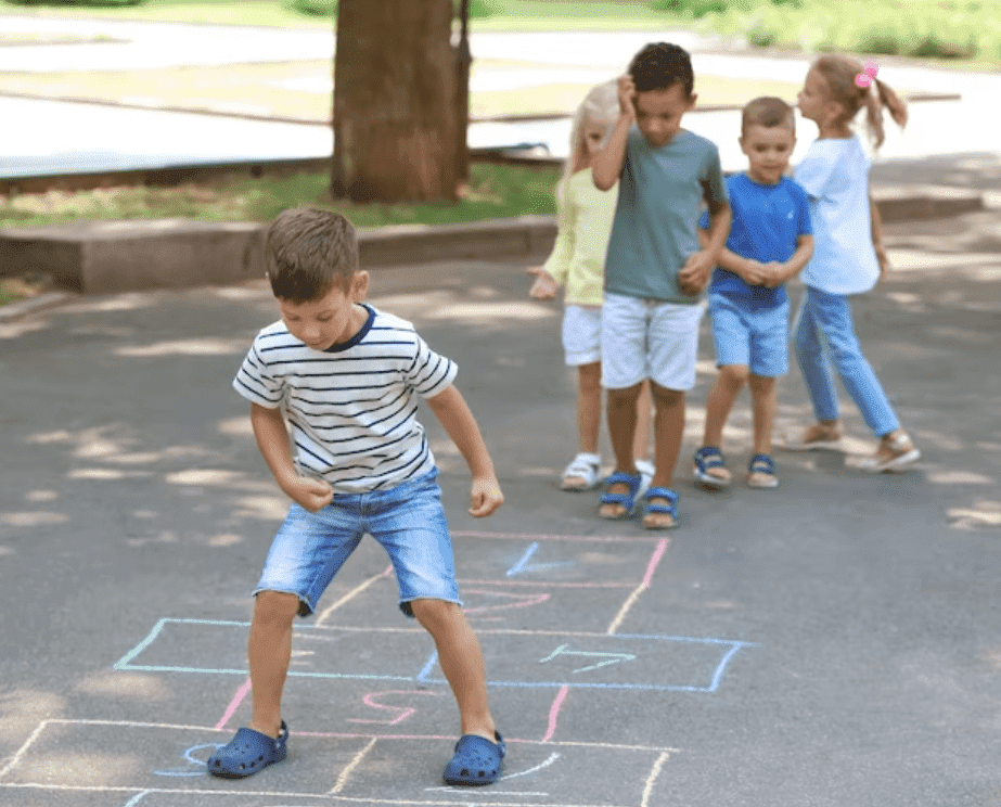 Crianças se divertindo muito brincando de amarelinha num parque