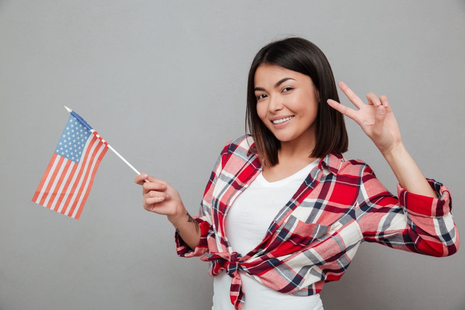 Mulher sorrindo segurando bandeira dos Estados Unidos porque está aprendendo diversas gírias em inglês