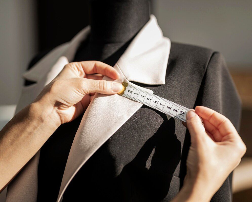 Profissional formado em Modelagem do Vestuário medindo o terno de um cliente.
