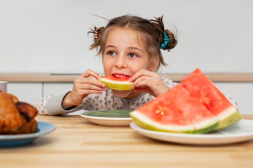 menina comendo melancia evitando a obesidade infantil