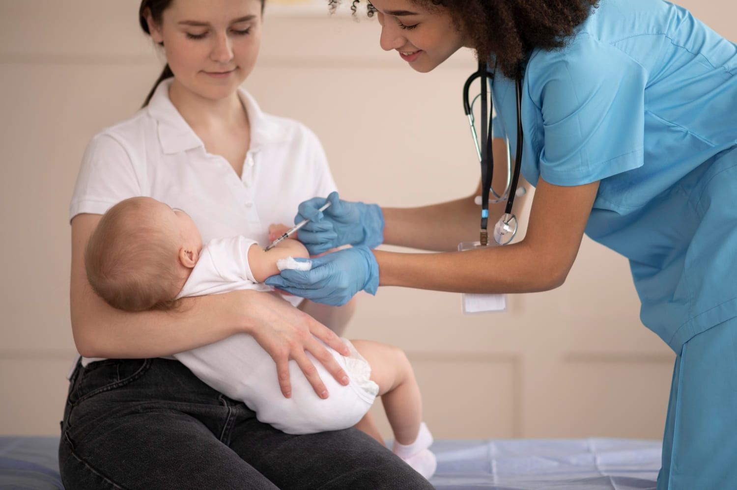 Bebê no colo da mãe sendo vacinado por uma técnica de enfermagem especializada em neonatologia e pediatria