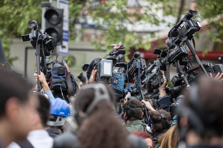 Imagem retrata repórteres cinegrafistas se aglomerando para filmagem.