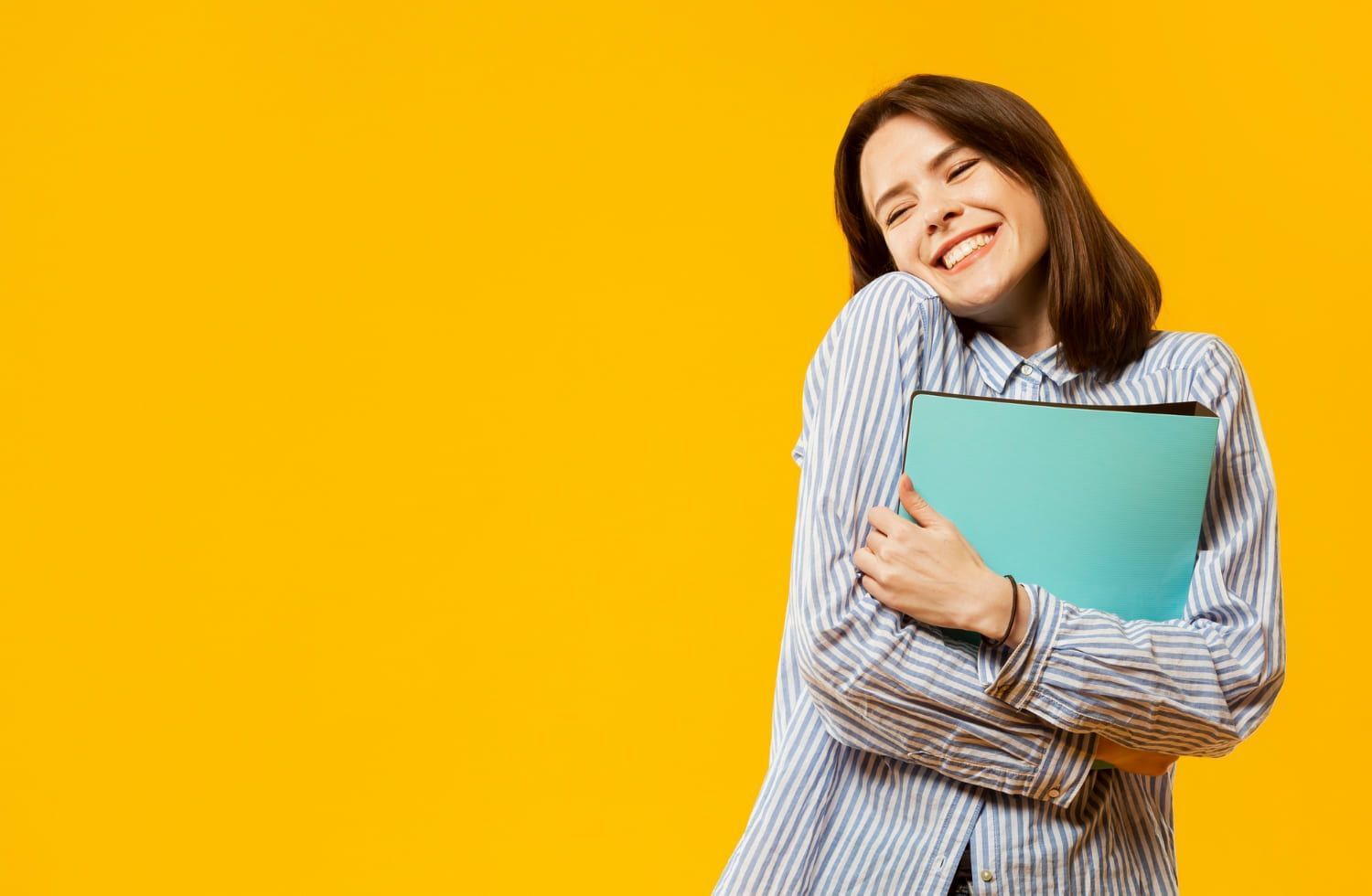 Jovem segurando livros e sorrindo; Setembro Amarelo: 4 estratégias infalíveis para dominar a ansiedade pré-prova