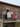 A group of people stood at the top of an external staircase, leaning over a mesh railing and smiling for camera. One person is holding a sign that says 'welcome CAMP Era KIN'