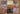 A photograph of nine small paintings on paper. The works are all different and consist of various abstract patterns and shapes in bright contracting colours and tones. The paintings have been placed together in a grid formation, and placed on what looks like a wooden floor.