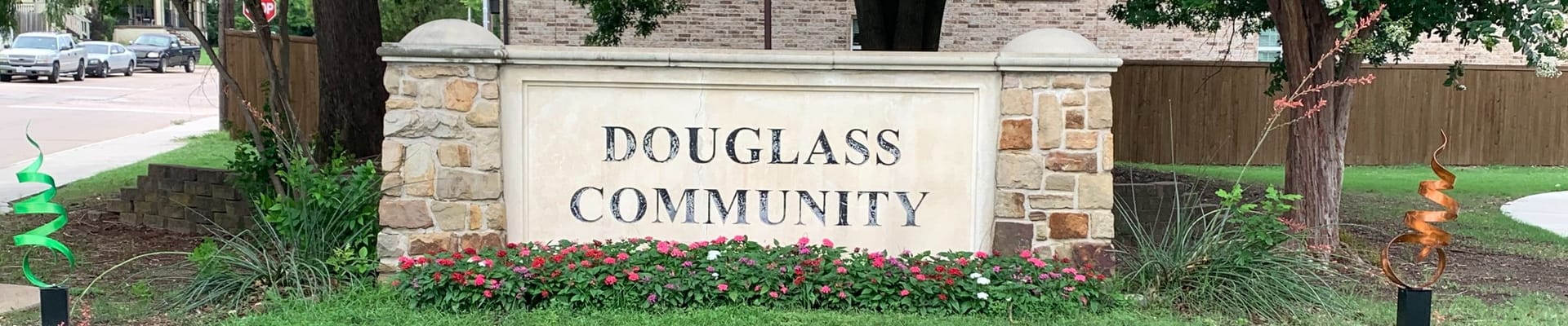 A photo of the Douglass Community entrance sign surrounded by flowers.