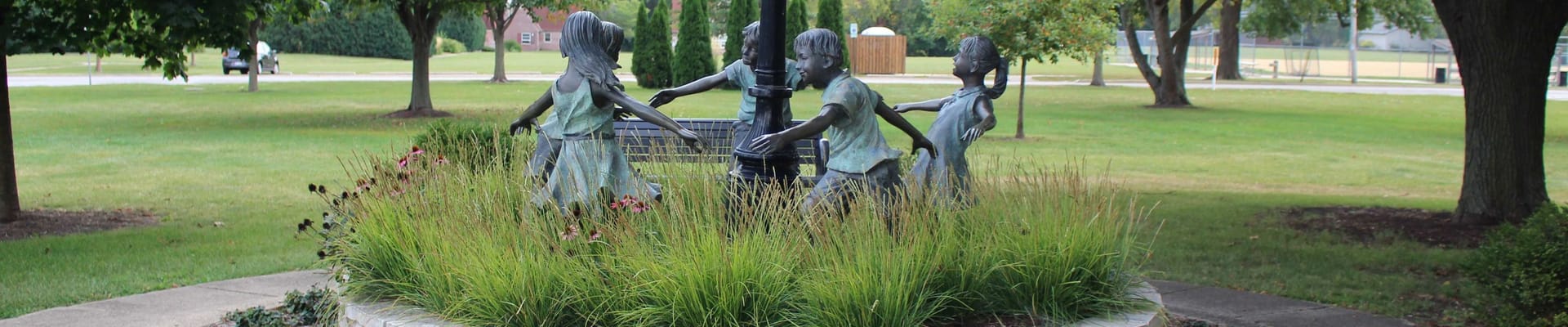 Image of statue in One Normal Plaza of children circling a pole