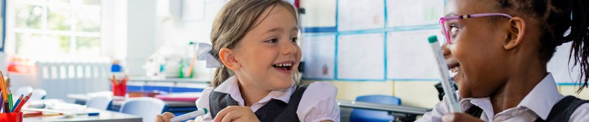 Decorative picture of two girls smiling in a classroom