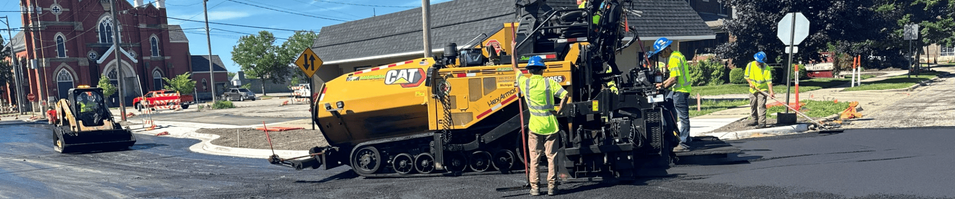 Road paving crew places new asphalt at the intersection of First Street and West Muskegon Avenue during street reconstruction.