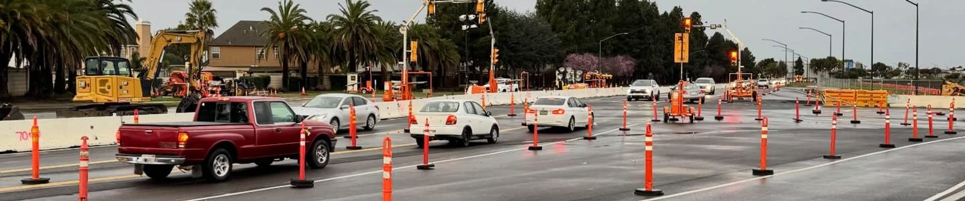 traffic and traffic cones in a road construction area with construction equipment and yellow traffic signals