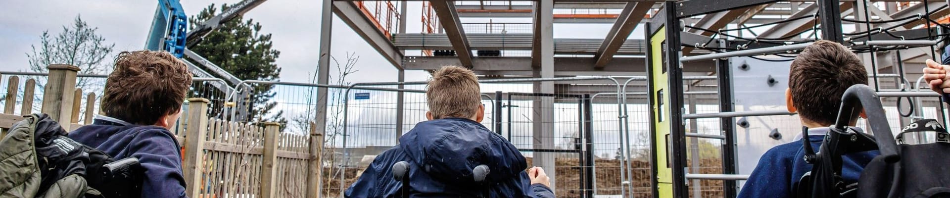 three people in wheelchairs are looking at a building site