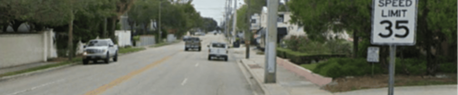 View of a street with cars and a speed limit sign