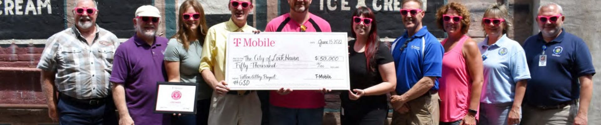 Photo of city officials, city staff, and T-Mobile representatives posing in Fallon Alley with a large check to celebrate the Fallon Alley Improvements project grant award.