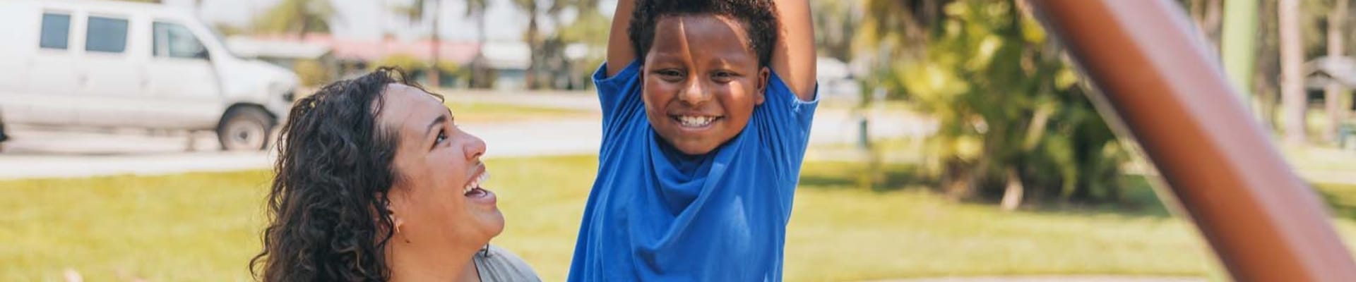 A mother and her son enjoying the monkey bars at a local park. 