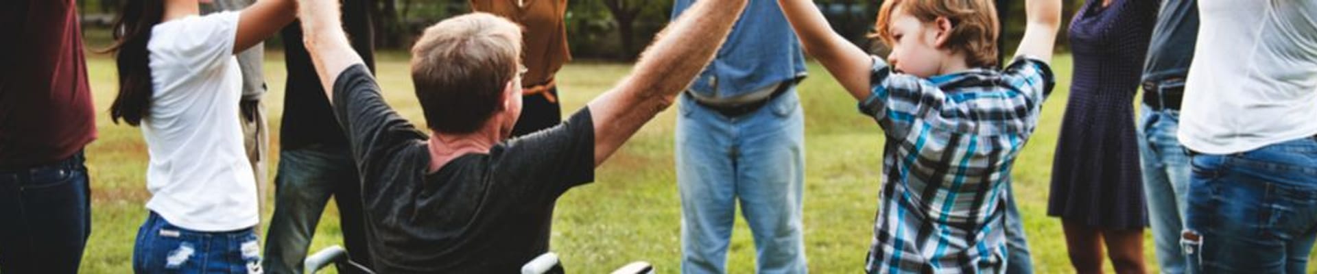 Decorative image showing a group of people holding hands in a circle in an outdoor space
