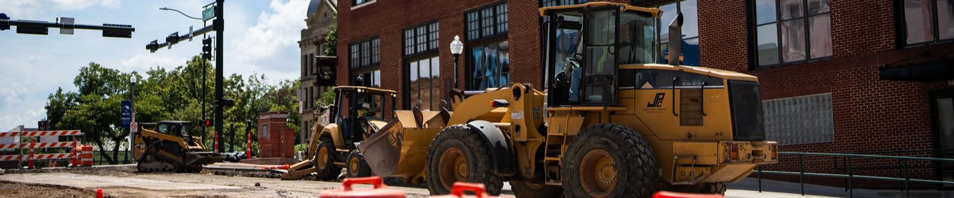 Construction Truck working on street next to red brick building with four way stop light