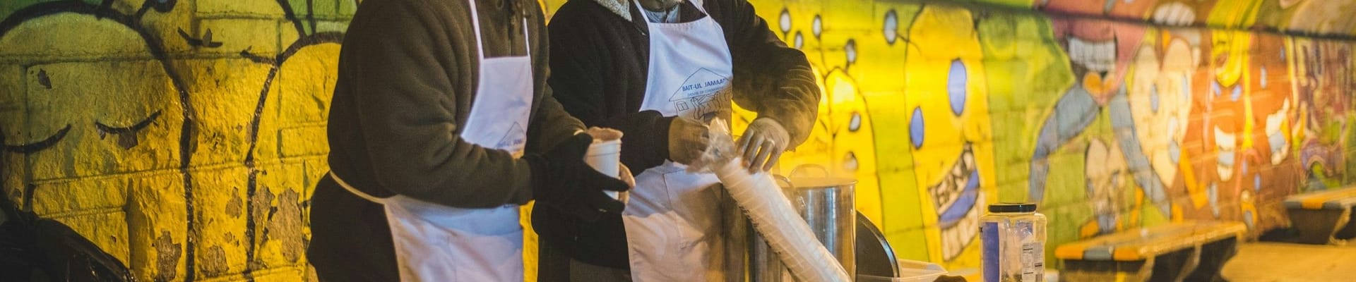 two men hosting a food table in a subway tunnel