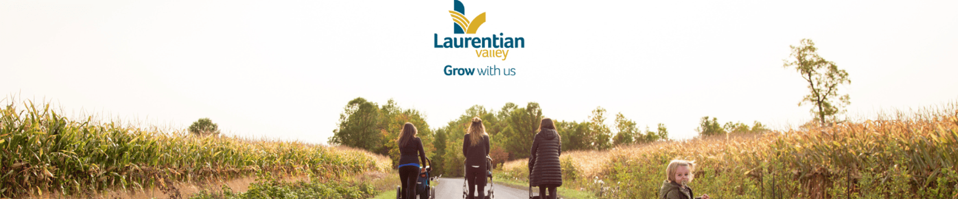 Photo of 3 women walking pushing strollers on the Algonquin Trail with a little toddler looking back towards the photographer.