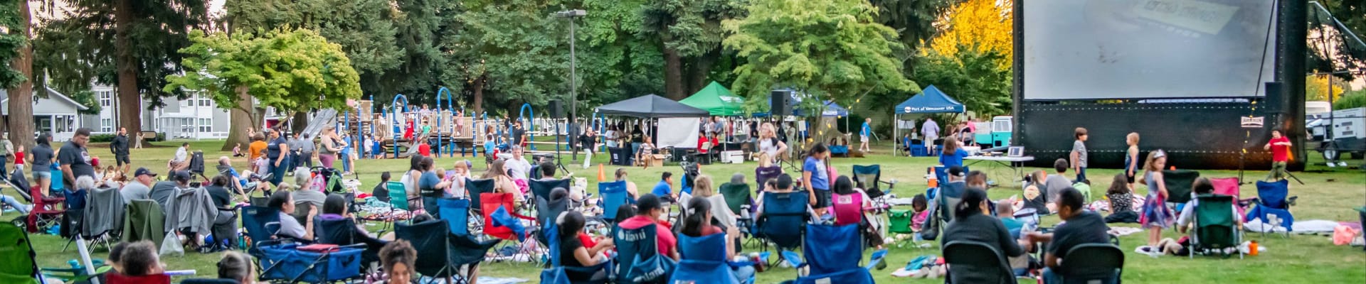 This photo shows a crowd of people sitting on chair and blankets, waiting for a Movie in the Park to begin at Fruit Valley Park.