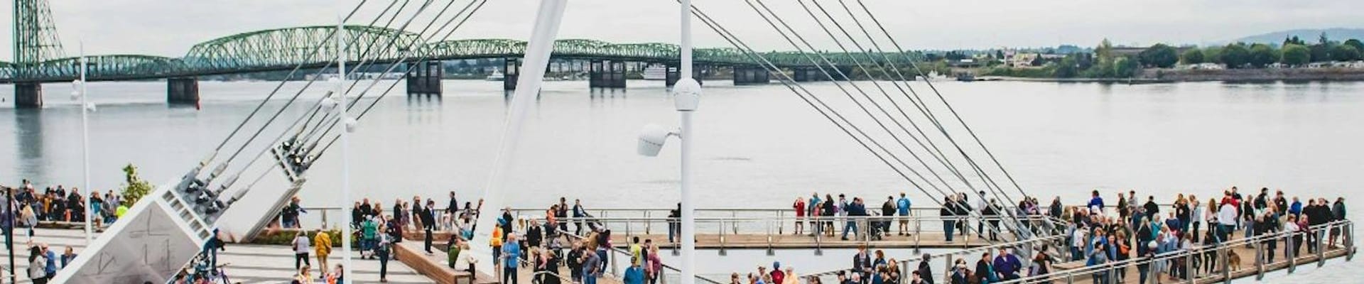 A photo of Grant Street Pier on the Vancouver Waterfront. This photo was taken the day the pier opened. It shows dozens of community members standing and walking on the pier, while the I-5 bridge stands in the background.