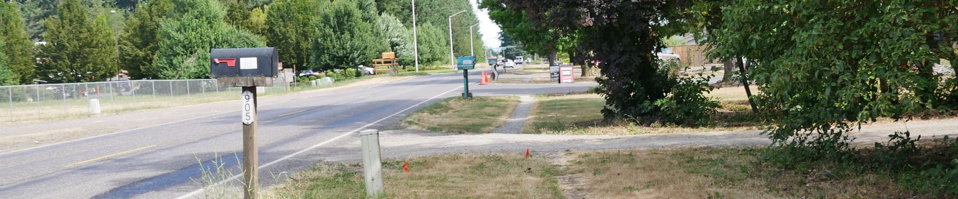 This photo shows the current east side of 192nd Avenue looking north. The side of the road includes a worn, dirt path that community members currently use to walk along the street. The street has no sidewalks in this area.
