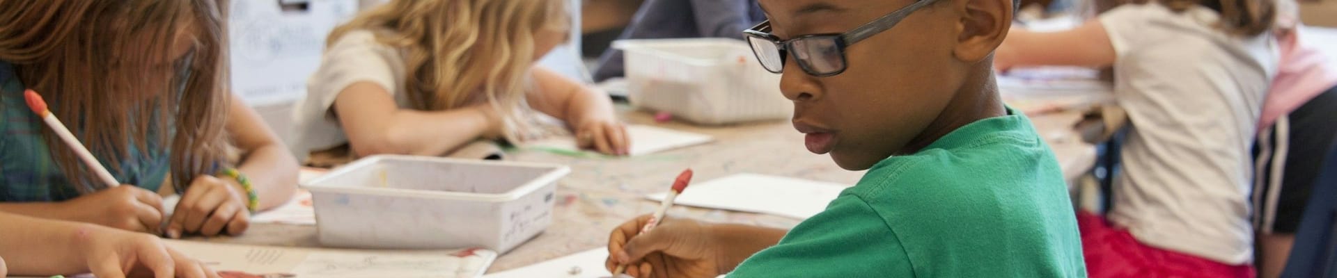 student in classroom learning to draw from an instructional book