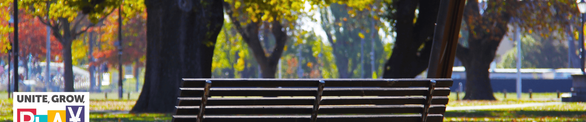 Park landscape with bench facing the park and parks logo in the left side corner