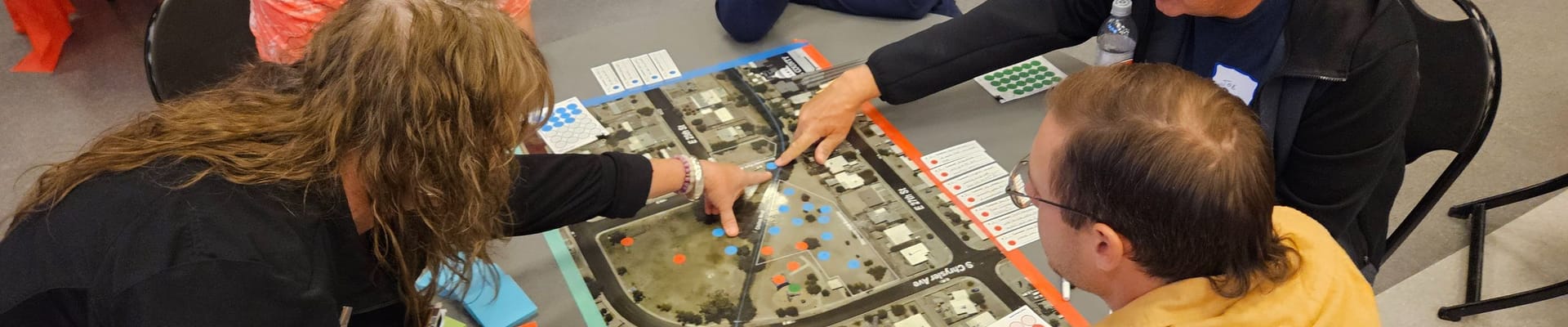 People sitting at a round table pointing to a map of a park