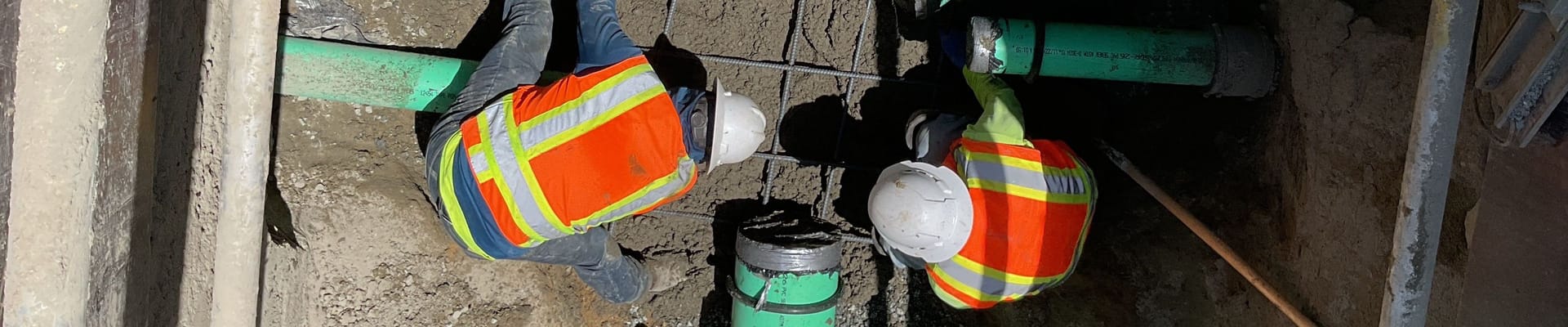 Overhead view of workers installing underground pipes.