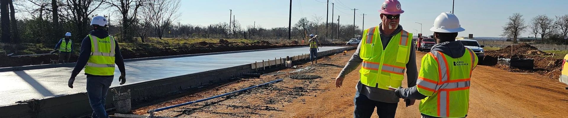 Construction on street with concrete being laid by construction workers