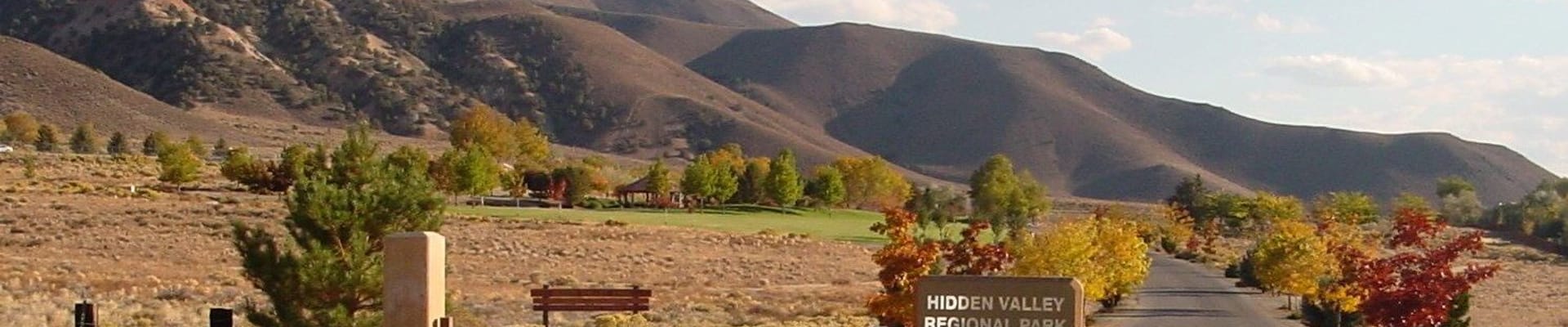 Hidden Valley Regional Park, featuring trees, park signage, road access, and mountains
