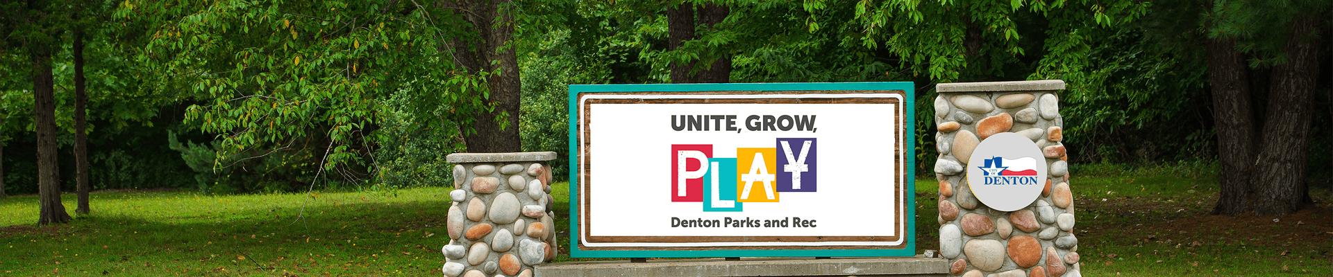 Photo with greenery in the background of a park with brick and rock name plaque that has the Parks and Recreation logo along with the City of Denton logo