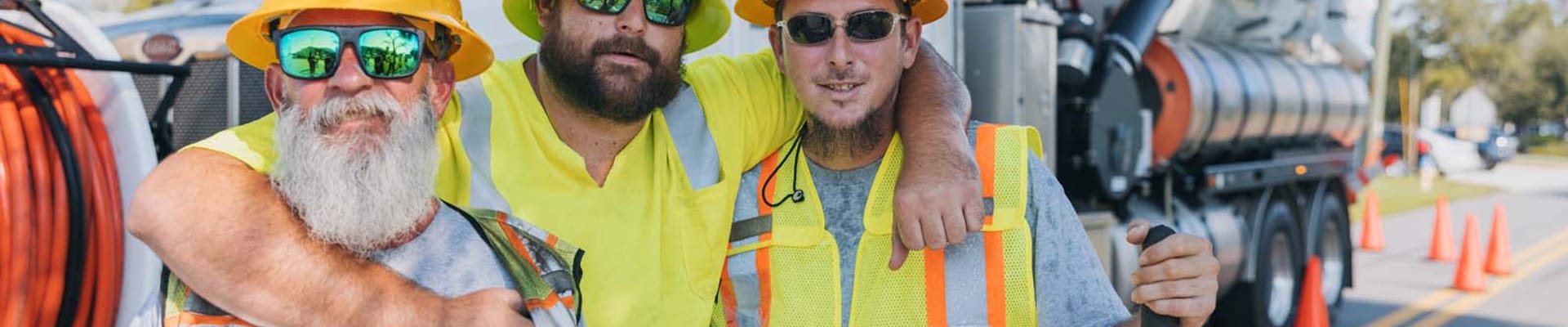 Three City workers standing in front of a City construction vehicle. 