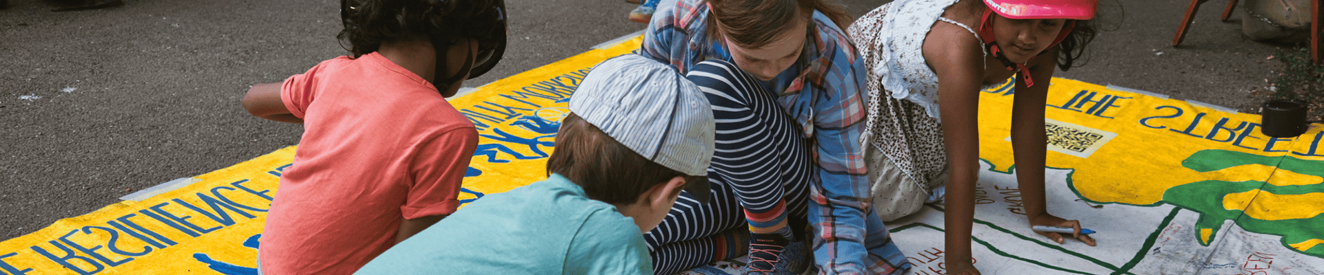 Children drawing climate related images on a large piece of paper spread across the floor