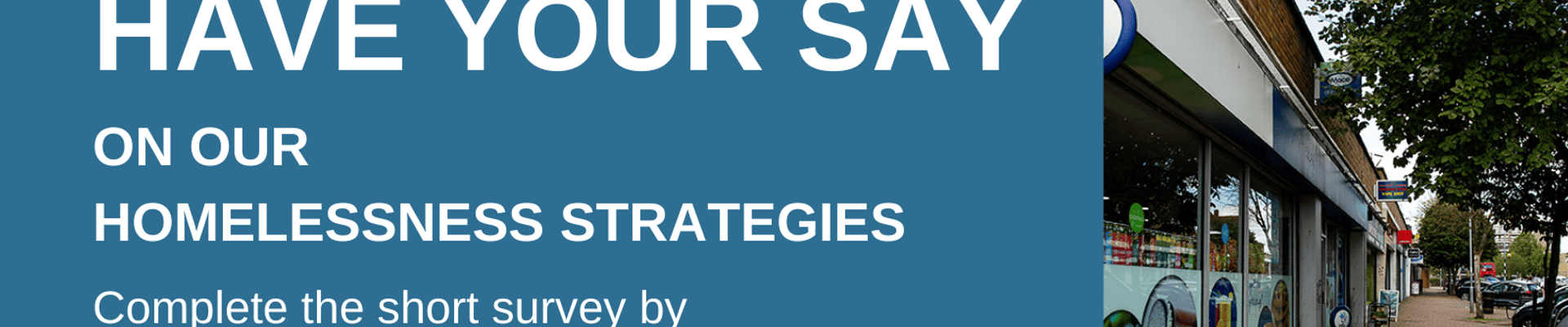 A row of shops next to trees, and a pavement.