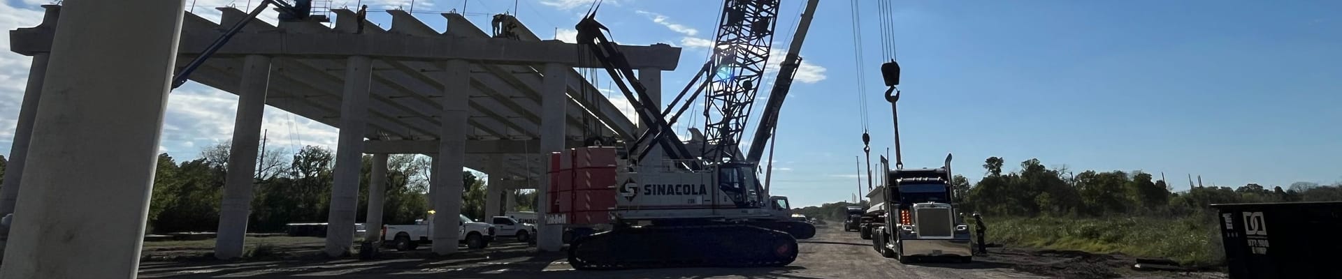 Construction trucks and construction taking place on gray bridge