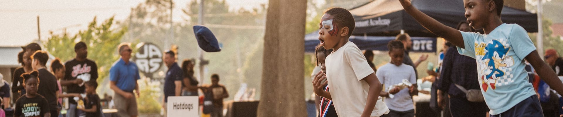 Three boys playing cornhole game outsite