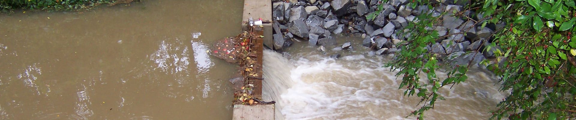 Photo of a stormwater water flowing through a constructed check dam. 