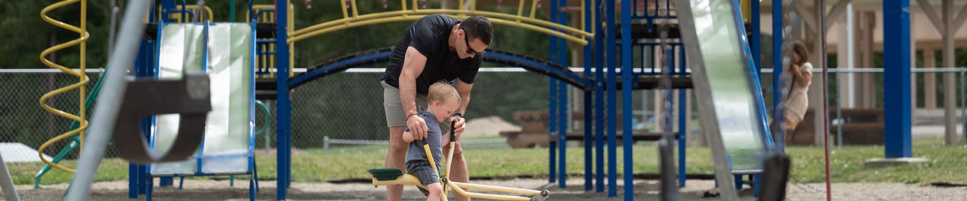 A father and son playing on a digging toy.