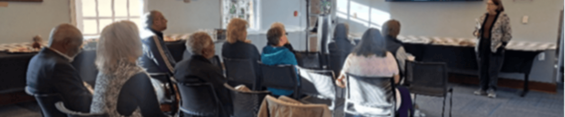 woman presenting information to a group of people sitting down in a meeting room
