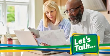 Couple reviewing finances looking at papers and a laptop.