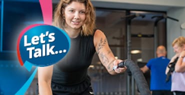 A middle aged lady holding a gym rope staying active in a gym