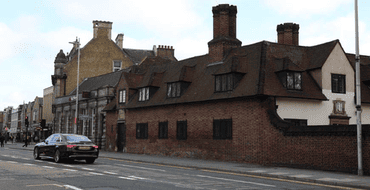 Street-level view of Ilford Approach featuring a historic brick building at a prominent corner site. The image highlights the area's heritage character and relationship to surrounding streets and development opportunities.