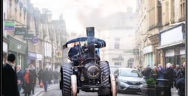 Image of a steam tractor going down the street with people watching 