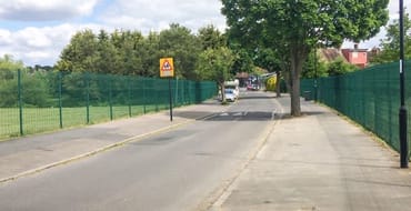 Section of road with no houses running between fenced grasslands on either side 