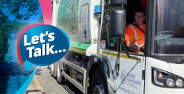 A council member of staff driving a recycling truck. He is in a hi-vis orange jacket and pulling the truck over to the side of the road to collect some recyclable home materials