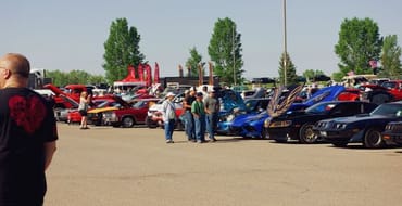 Crowd viewing rows of colorful cars at an outdoor car show in Laramie.